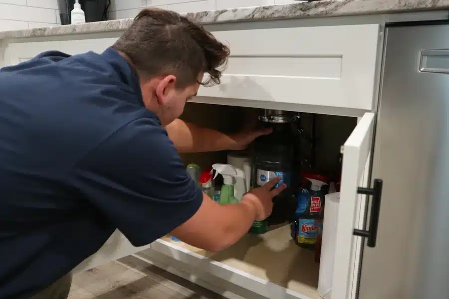 Plumber installing a garbage disposal under kitchen sink in Acworth, GA