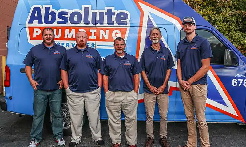 Absolute Plumbing technicians standing in front of a work van in Canton, GA