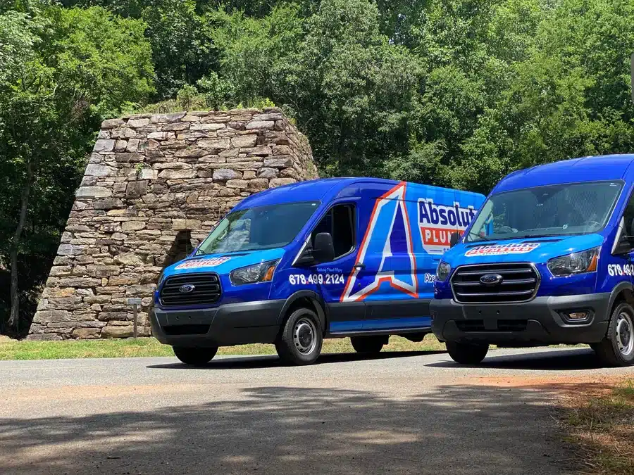 Two Absolute Pluming vans parked outside in Acworth, GA