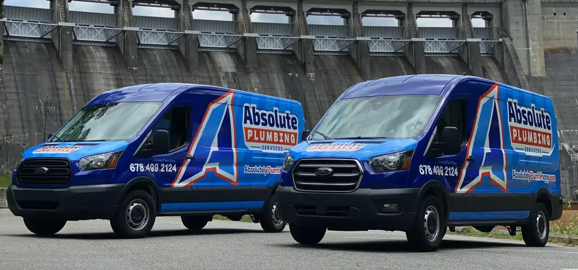 Two Absolute Pluming Vans parked outside near a dam in Cobb County, GA